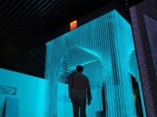 man in black jacket standing on blue lighted room