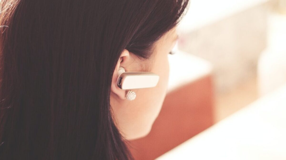 Woman Wearing Earpiece Using White Laptop Computer