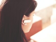 Woman Wearing Earpiece Using White Laptop Computer