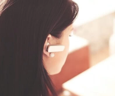 Woman Wearing Earpiece Using White Laptop Computer