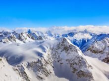 Areal Photography Of Snow Coated Mountains Under Clear Blue Sky