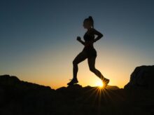 silhouette of man jumping on rocky mountain during sunset