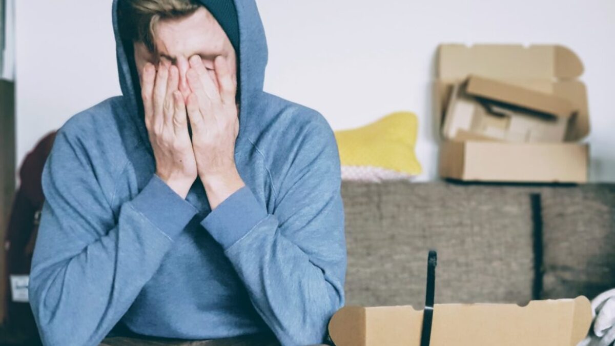 man covering face with both hands while sitting on bench