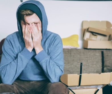 man covering face with both hands while sitting on bench