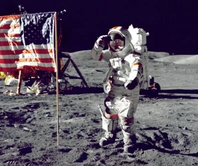 astronaut standing on moon beside U.S.A. flag