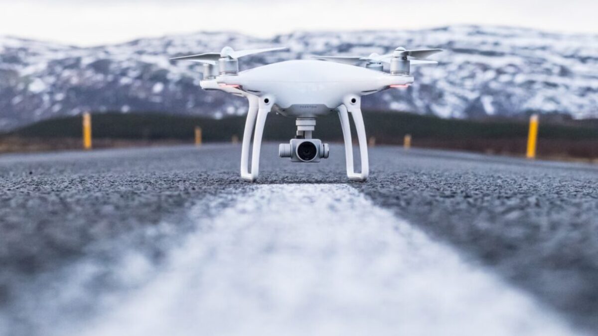 white quadcopter on gray concrete road top during daytime