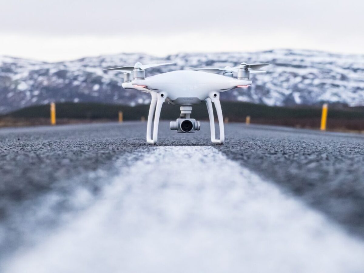 white quadcopter on gray concrete road top during daytime