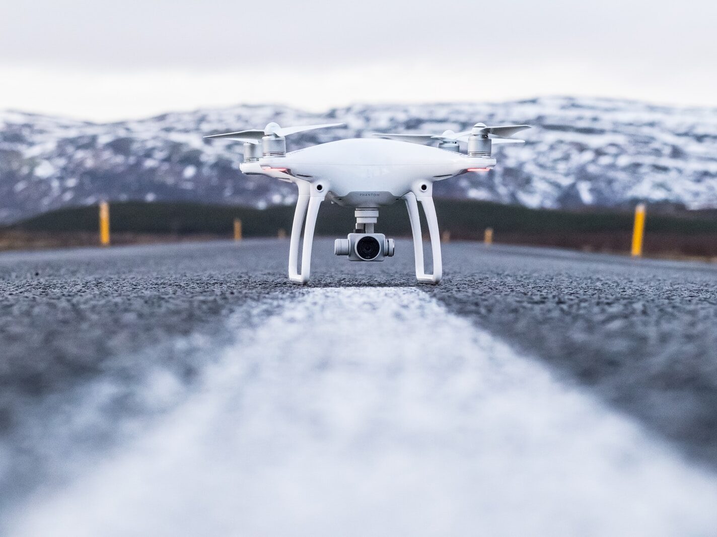 white quadcopter on gray concrete road top during daytime