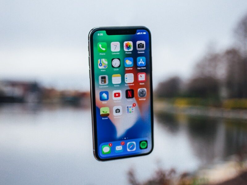 silver iPhone X floating over open palm