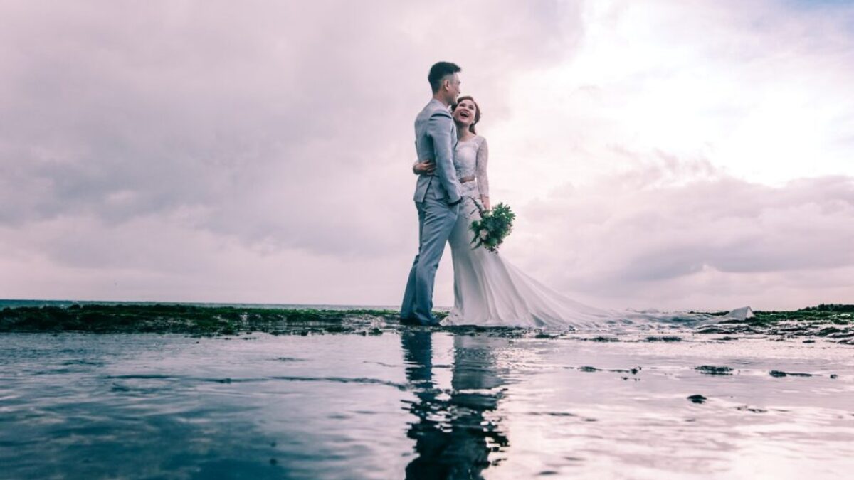 Man in Gray Dress Suit Jacket Embraces Woman Wearing Wedding Gown