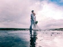 Man in Gray Dress Suit Jacket Embraces Woman Wearing Wedding Gown