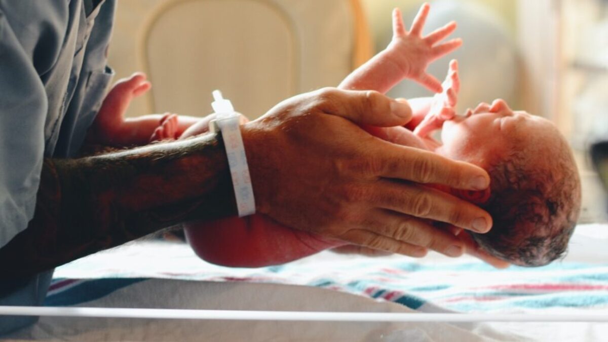 person wearing gray shirt putting baby on scale