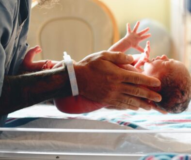 person wearing gray shirt putting baby on scale