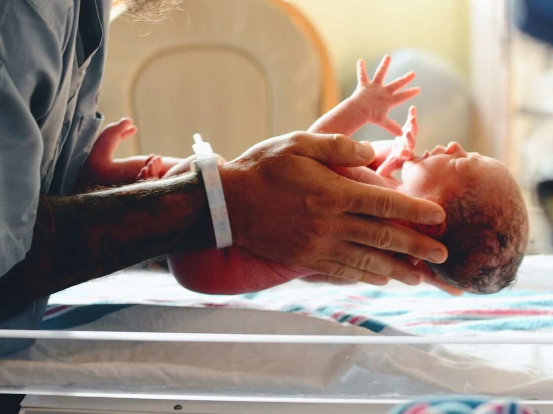 person wearing gray shirt putting baby on scale