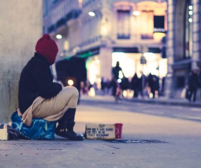 person sitting beside building looking straight to the street at golden hour