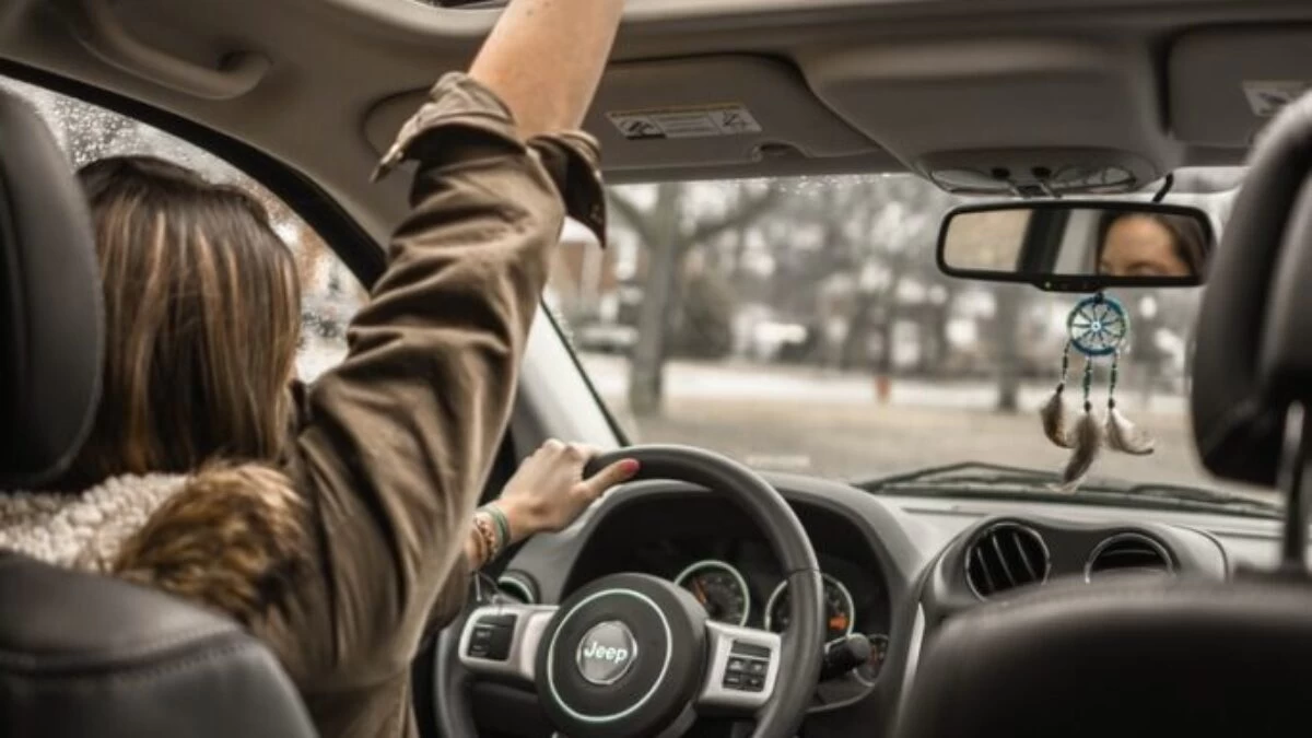 woman raising her right hand inside black and brown vehicle