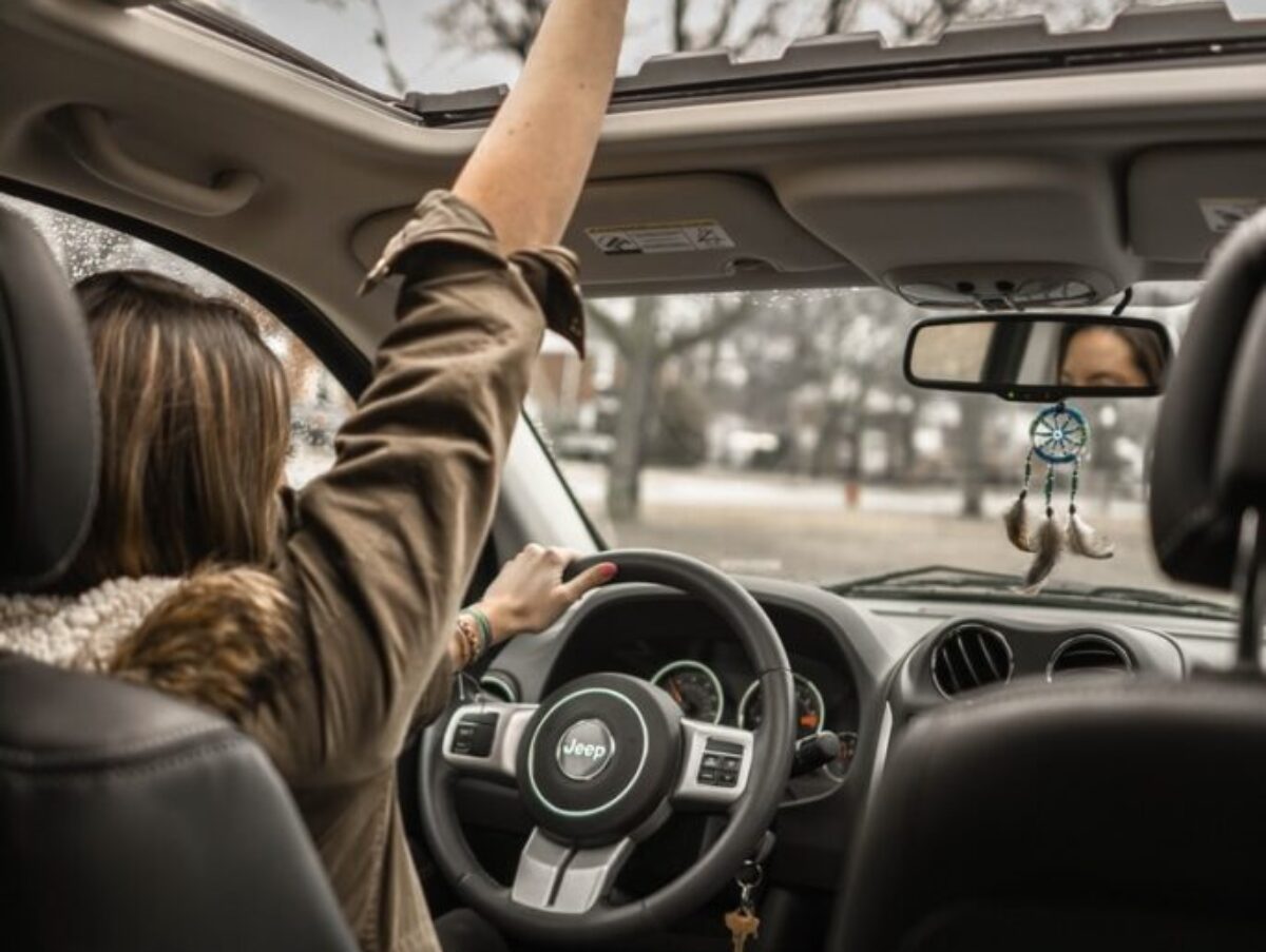 woman raising her right hand inside black and brown vehicle
