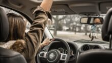 woman raising her right hand inside black and brown vehicle