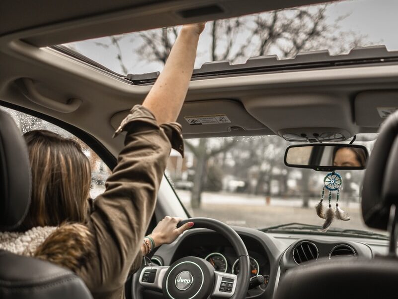 woman raising her right hand inside black and brown vehicle