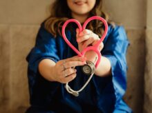 girl in blue jacket holding red and silver ring