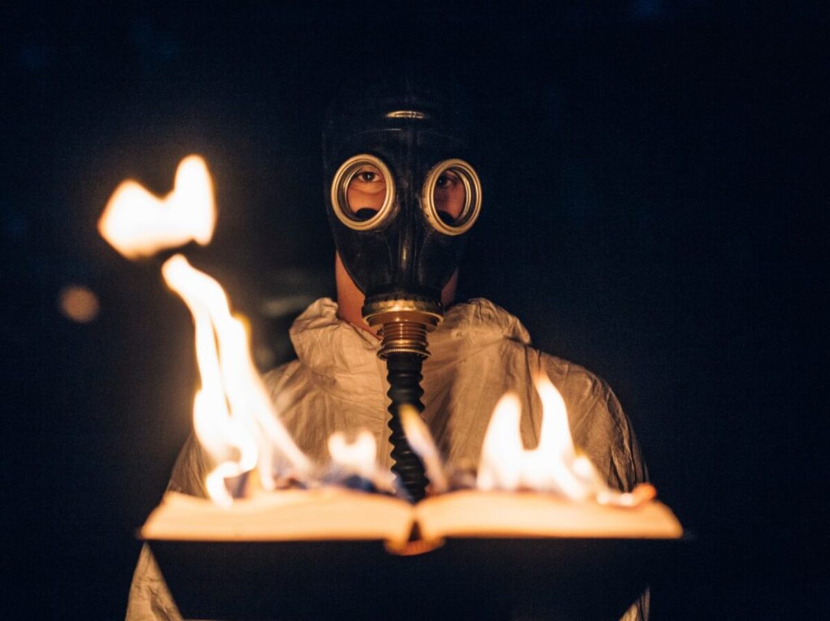 person wearing gas mask holding fire