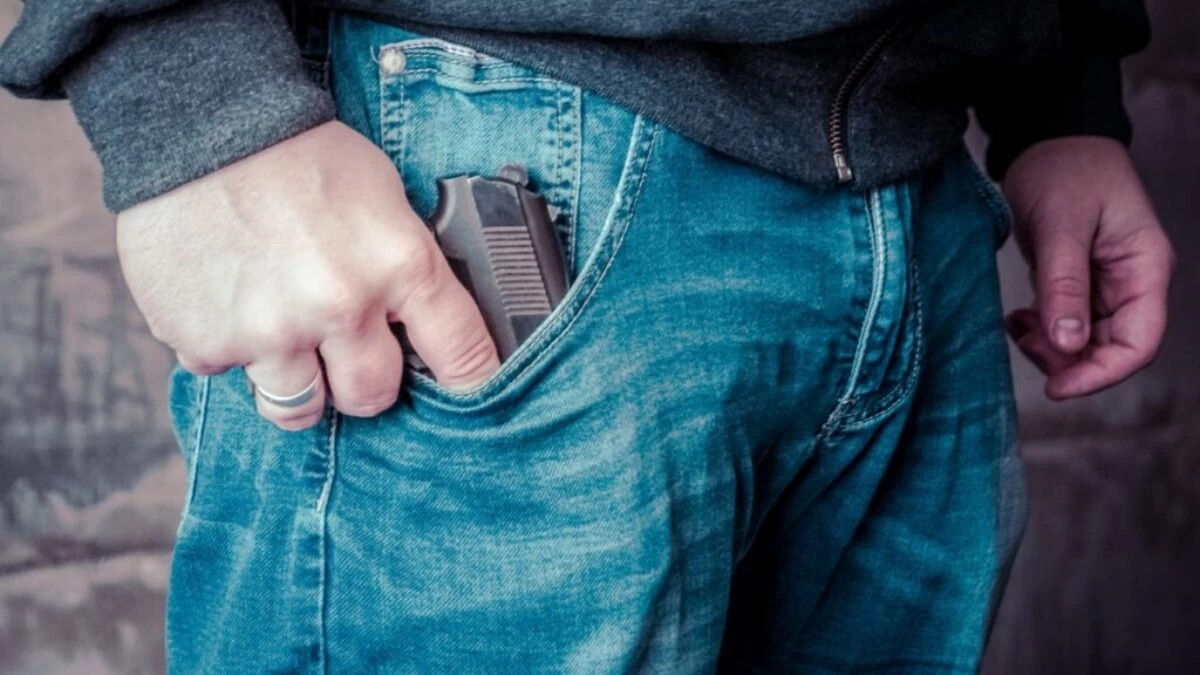 person in blue denim jeans holding black semi automatic pistol