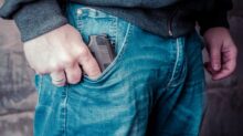 person in blue denim jeans holding black semi automatic pistol
