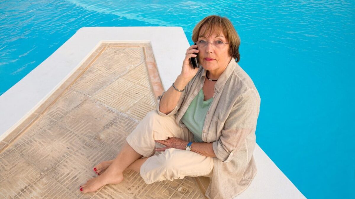 woman in brown coat sitting on brown wooden dock