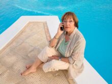 woman in brown coat sitting on brown wooden dock