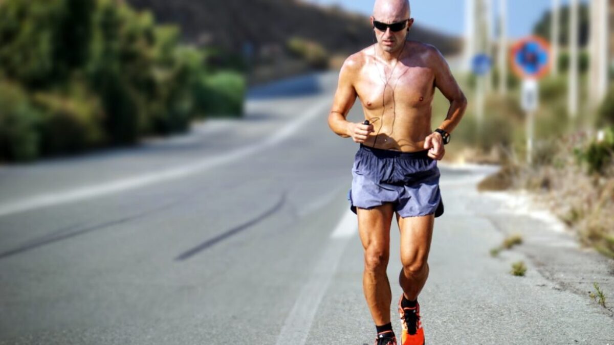 man jogging while listening using black earphones during day time