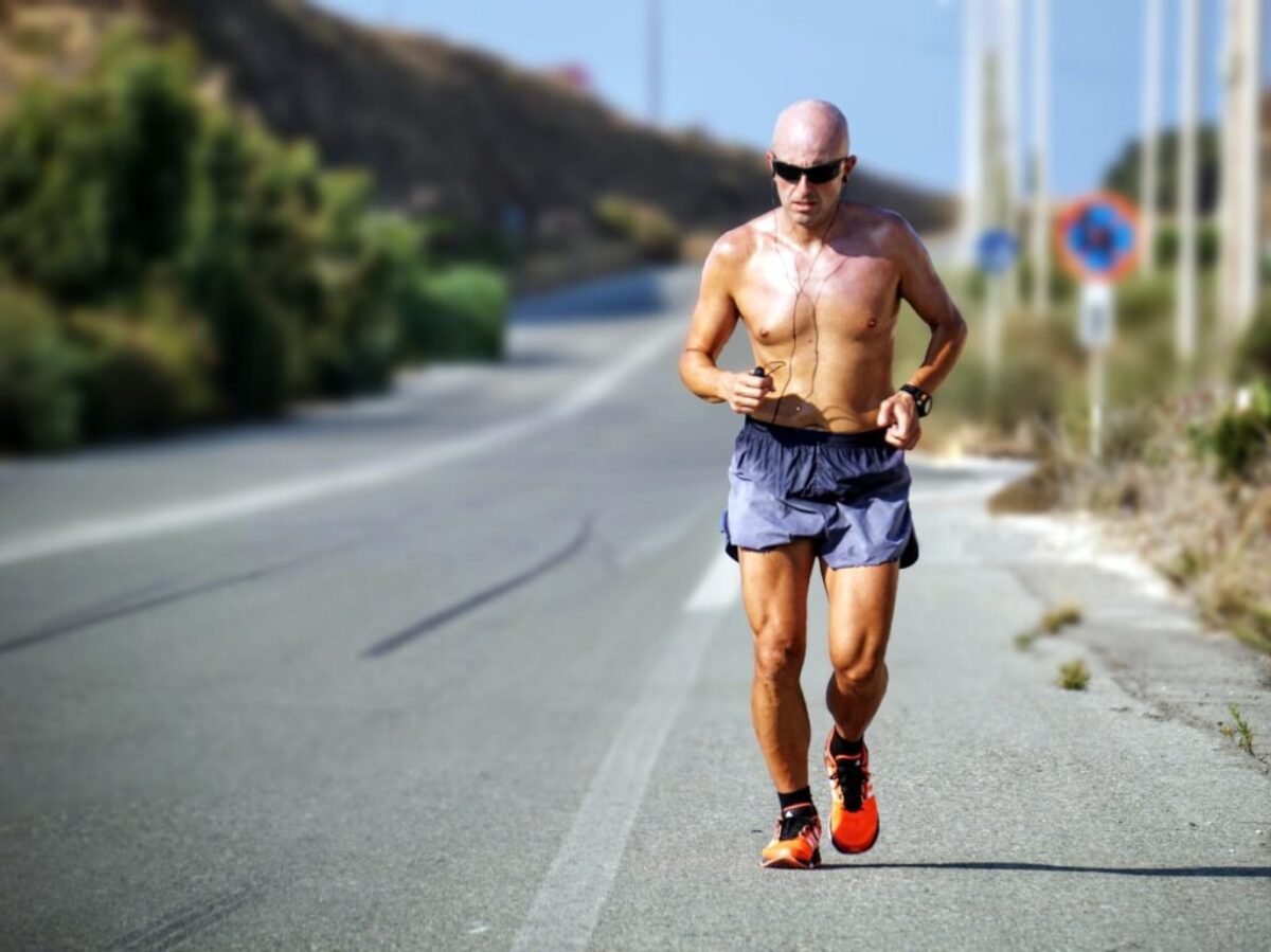 man jogging while listening using black earphones during day time