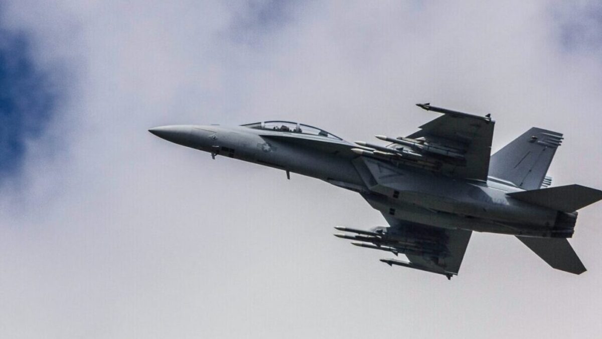 fighter jet flying under white clouds