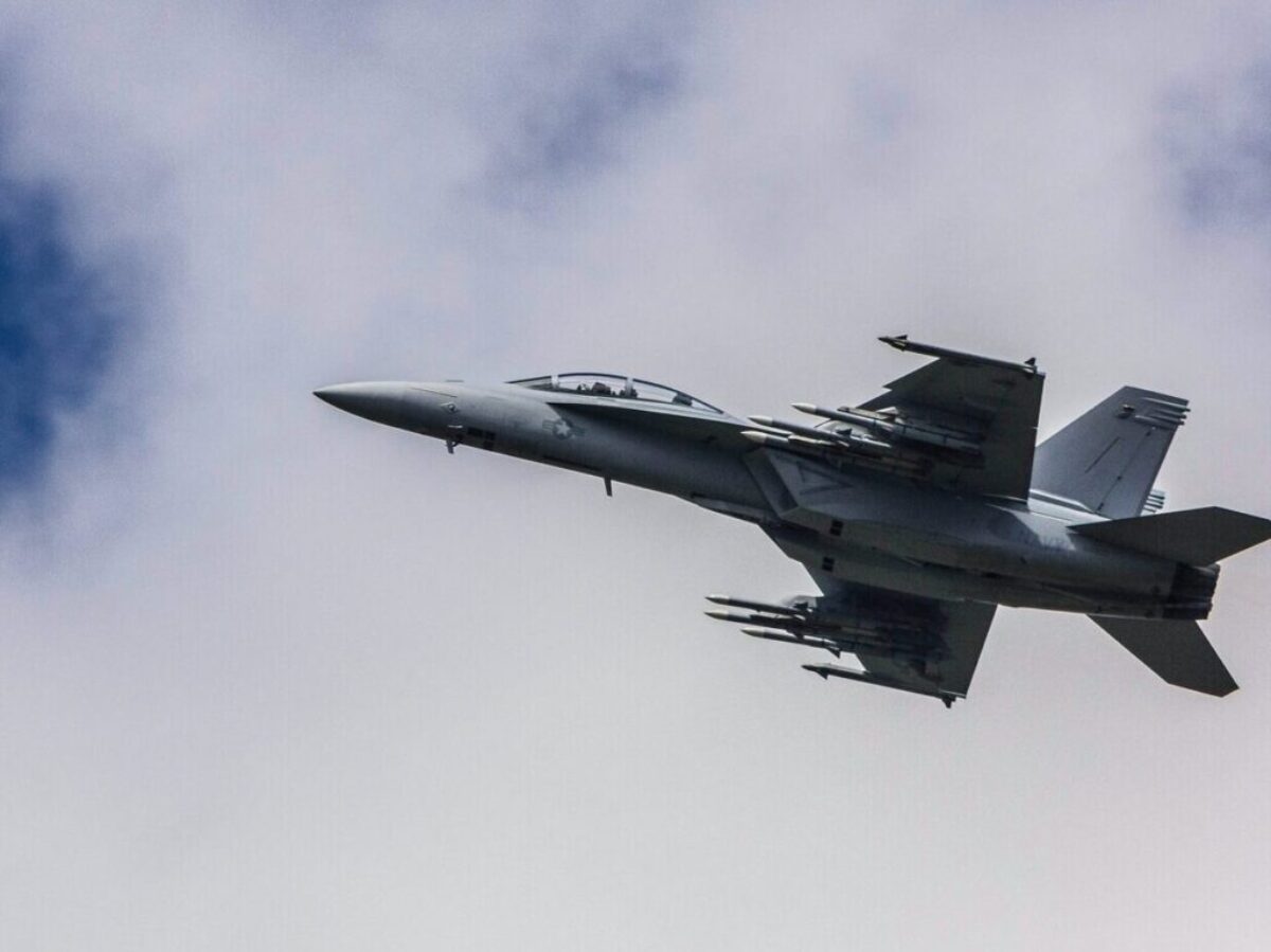 fighter jet flying under white clouds