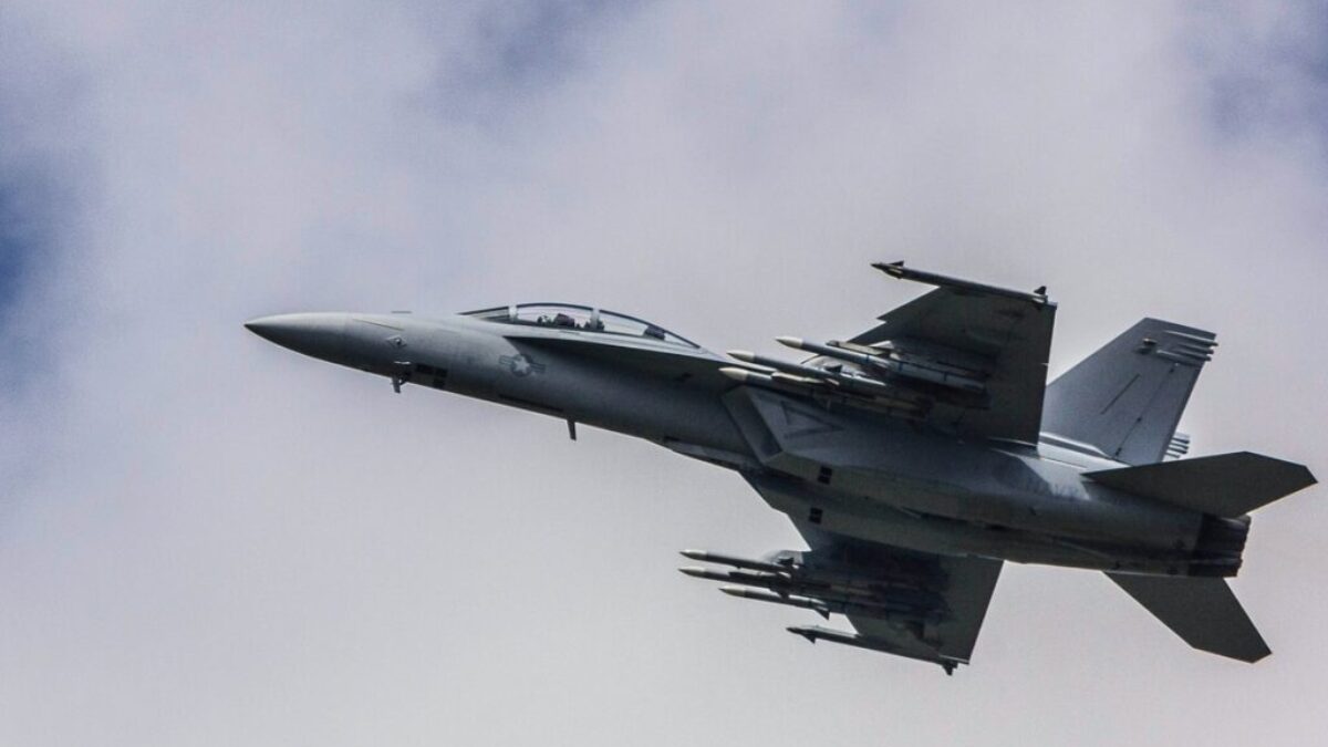 fighter jet flying under white clouds