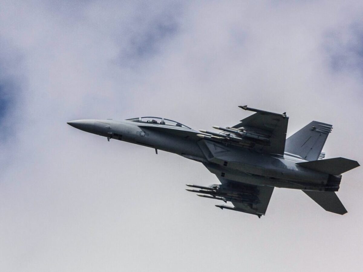 fighter jet flying under white clouds
