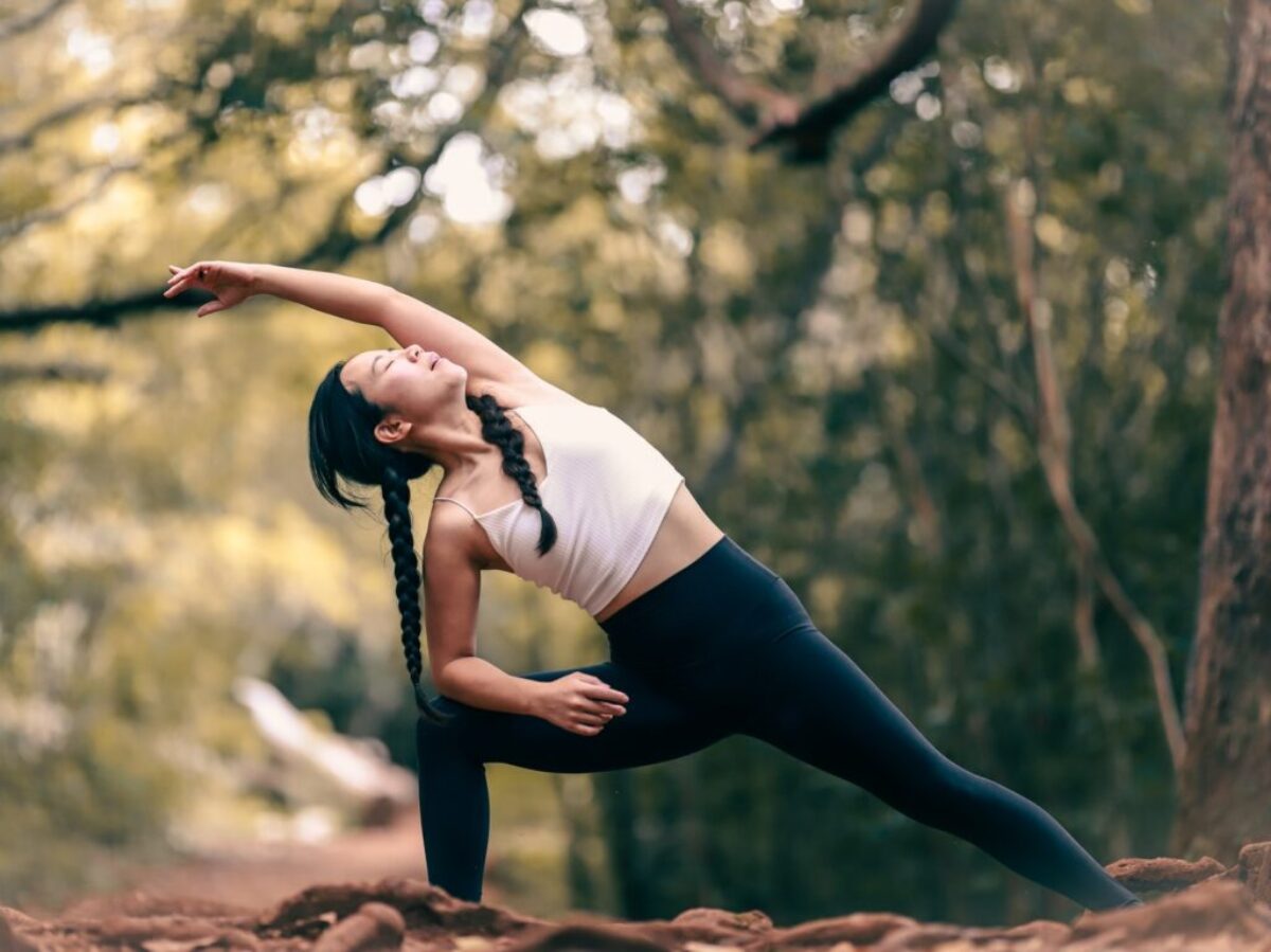woman in white tank top and black leggings doing yoga during daytime