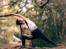 woman in white tank top and black leggings doing yoga during daytime