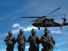 Four Soldiers Carrying Rifles Near Helicopter Under Blue Sky