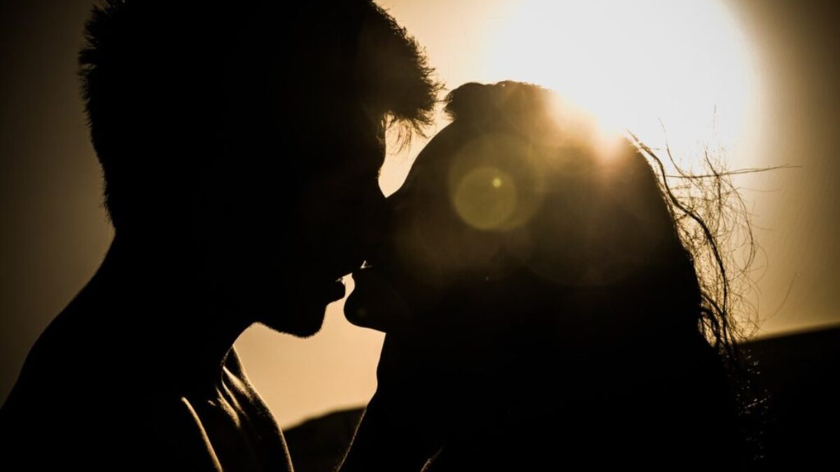 Silhouettes of Couple Kissing Against Sunset