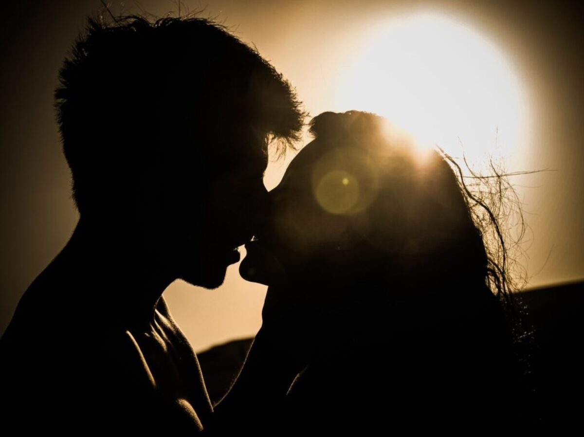 Silhouettes of Couple Kissing Against Sunset