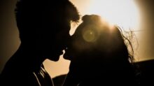 Silhouettes of Couple Kissing Against Sunset