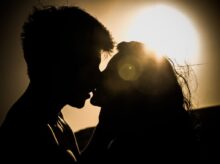 Silhouettes of Couple Kissing Against Sunset