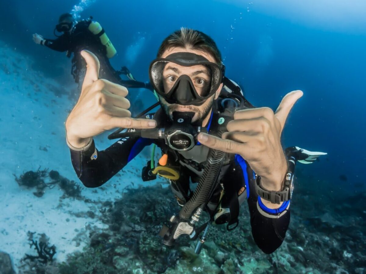 man underwater making hand signs