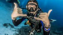 man underwater making hand signs