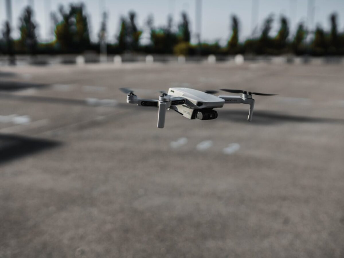 white and black drone on gray concrete ground during daytime