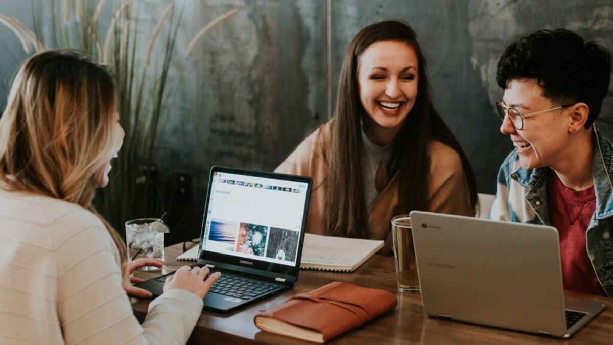 three people sitting in front of table laughing together