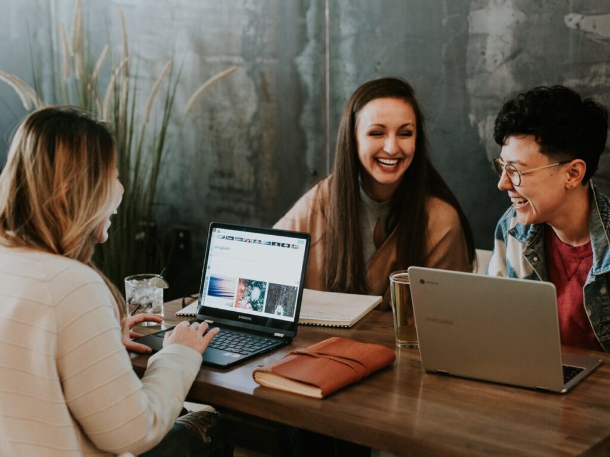 three people sitting in front of table laughing together