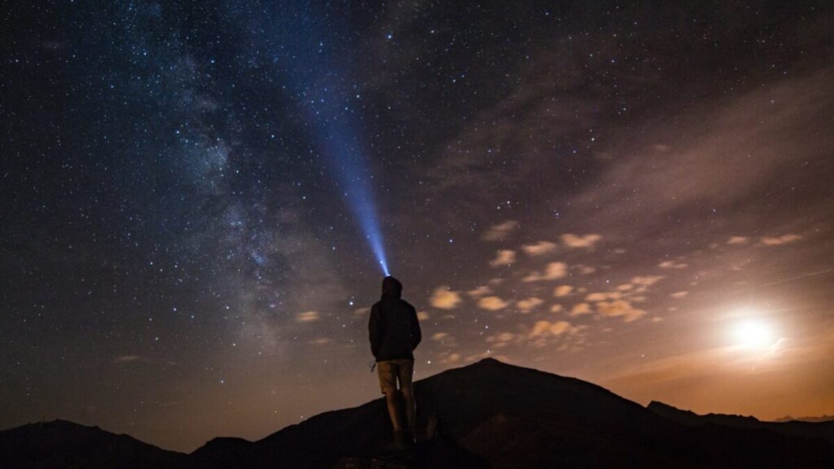 man standing at mountain peak under starry night sky