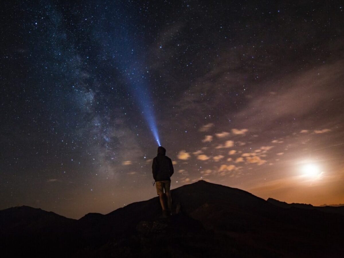 man standing at mountain peak under starry night sky