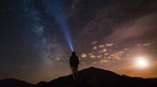 man standing at mountain peak under starry night sky